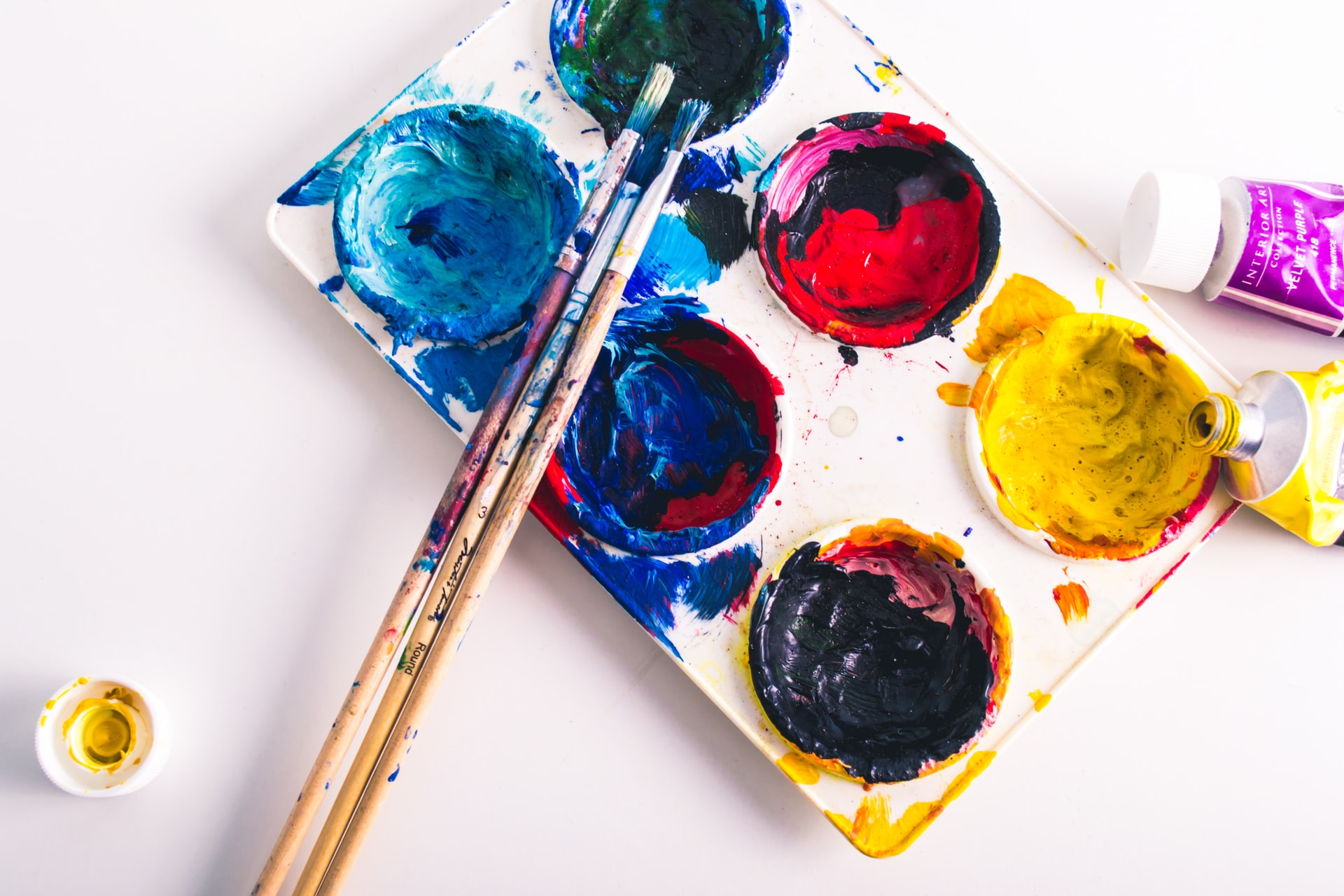 A messy paint palette and paintbrushes. Art can be an accessible hobby for chronically ill people.